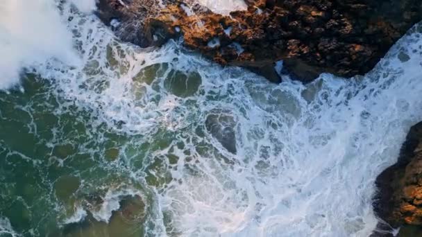 海岸の岩の上で強力な海の波が衝突する 白い泡がゆっくりと動き出す火山ビーチの崖には 美しいラフ海の水が飛び散っています 劇的な海辺の風景ズームオン — ストック動画