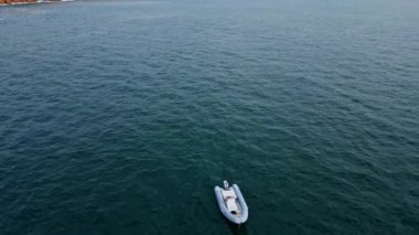 Şişme tekne sonsuz deniz manzarası yaklaşıyor. Gri derin okyanusta seyreden lüks sürat teknesinin havadan görüntüsü. Kauçuk sal, deniz yolculuğunda sakin bir körfezde süzülüyor. Deniz eğlencesi macera konsepti