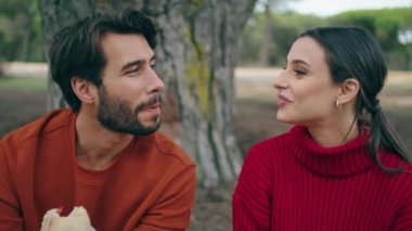 Rahat genç çift güzel ormanda pikniğin tadını çıkarıyor. Sakallı bir adamla lezzetli sandviçler yiyen neşeli bir kadın. Gülümseyen turistler romantik bir hafta sonunda doğada dinleniyorlar..