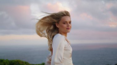 Okyanus manzarasını yöneten şefkatli bir kadın. Neşeli kız günbatımı doğasında vakit geçiriyor. Deniz ortamının tadını çıkartan tatmin olmuş bir kadın. Gülümseyen kız tatilde omzunun üzerinden bakıyor. 