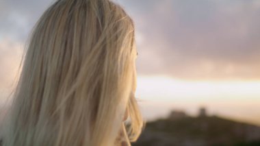 Şehvetli kadın kale sıcacık portresi arıyor. Rahat model, sonbahar akşamı doğasında kameraya dönüşüyor. Sarışın kadın deniz manzaralarını seyrediyor, şatoyu kapatıyor. Açık havada poz veren turist kız.