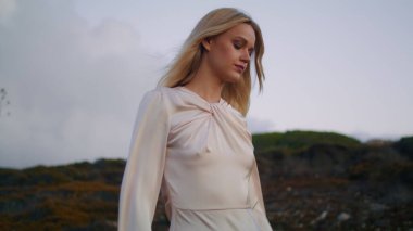 Yeşil bitkilerle doğa yürüyüşü yapan ciddi bir kız. Düşünceli kadın, gün batımında el değmemiş bir tepeye doğru ilerliyor. Sarışın manken akşam manzarasına uzaktan bakıyor. İnsanlar ve çevre kavramı