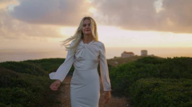 Işıldayan bayan şatonun tepesinde tek başına yürüyor. Gülümseyen kız, gün batımı vadisinin arkasına bakıyor. Rahat kadın dokunulmamış doğanın tadını çıkarıyor. Deniz manzarasını inceleyen sarışın model kameraya doğru dönüyor.