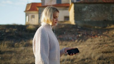 Şato manzaralarında kulaklık takan sakin bir bayan. Sonbahar Tepesi portresinde müzik dinleyen sarışın kadın. Akıllı telefon taşıyan süveter kız kuru sahaya gidiyor. Çayırı tek başına geçen sevimli bir model. 