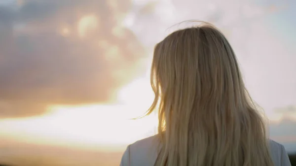 迷人的女士欣赏日落的天空特写 金发女人从肩像上方看相机 温文尔雅的姑娘一个人看着夏夜的风景 女性模特儿呈现多云的自然背景 — 图库照片