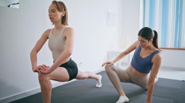 Spor kızları hafif iç mekanlarda çömelme egzersizleri yapıyorlar. Atletik kadınlar vücut geliştirme antrenmanında hamleler yaparak güç gösterisi yapıyorlar. Formda antrenör öğrenci ısınma egzersizlerinin keyfini çıkarın. 