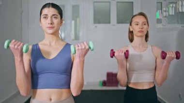 Deniz feneri kapanışında spor yapan iki dambıl. Atletik kadınlar vücut geliştirme antrenmanlarında güç gösterisi yapıyorlar. Ağırlık tutan arkadaşlar birlikte egzersiz yapıyorlar. 