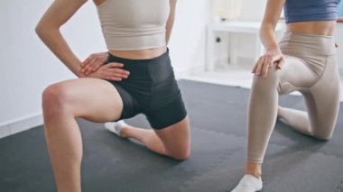 Yoga odasında bacaklarını esneten kadın sporcular. Bilinmeyen zayıf, esnek bayanlar lastik hasırda vücut çalıştırıyor. Tanımlanamayan bir spor çifti evde spor yaparken eğleniyor.