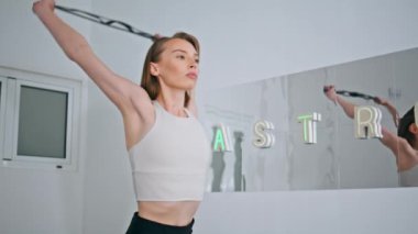 Motivasyonlu sporcu evde bant egzersizleri yapıyor. Odaklanmış zinde bir kadın beyaz bir dairede çok çalışıyor. Sakin bayan kauçuk direnci genişleticisi yalnız çalışıyor. Stüdyoda sağlıklı kız fitness eğitimi