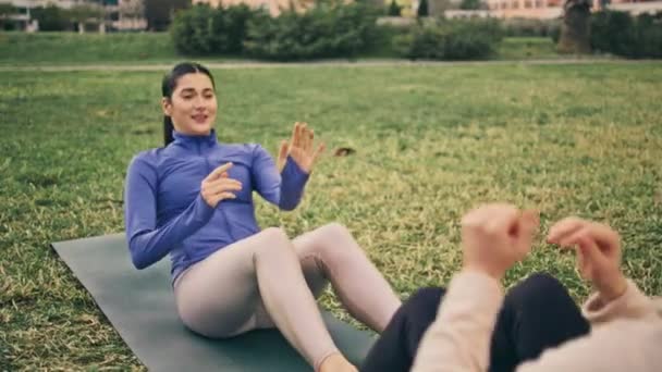健康的女人在户外拍手叫好 两个积极的女友在夏季公园里和5岁的女孩一起做伙伴仰卧起坐练习 以体育运动为重点的夫妇瑜伽垫力量锻炼 — 图库视频影像