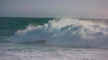 Fırtına dalgaları okyanus yüzeyinde beyaz köpük yapıyor. Süper ağır çekimde güçlü sörf fıçıları. Manzaralı deniz suyu dalgalanan kıyılar sığ. Güneşli yaz gününde çarpıcı bir deniz manzarası..