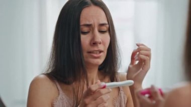 Aynalı yerde hamilelik testi tutan stresli bir kız. Korkmuş bir kadın banyoda plansız bir bebek için üzülüyor. Endişeli kadın hamile test sonuçları evde tepkimeye giriyor. İstenmeyen çocuk konsepti