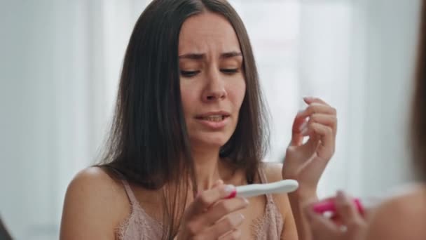 鏡のところで妊娠検査をしているストレスのある女の子 バスルームで計画外の赤ちゃんのために悲しい感じ怖がっている女性を閉じます 妊娠検査の結果が自宅で反応することを心配しました 望まない子供の概念 — ストック動画