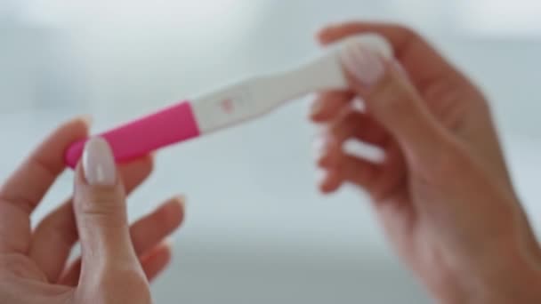 自宅のクローズアップで妊娠検査を手 トイレで喜んで肯定的な結果を探している無名の女性 白い場所に子供が立っていると予想される男性の指の女の子 将来の妊産婦概念 — ストック動画