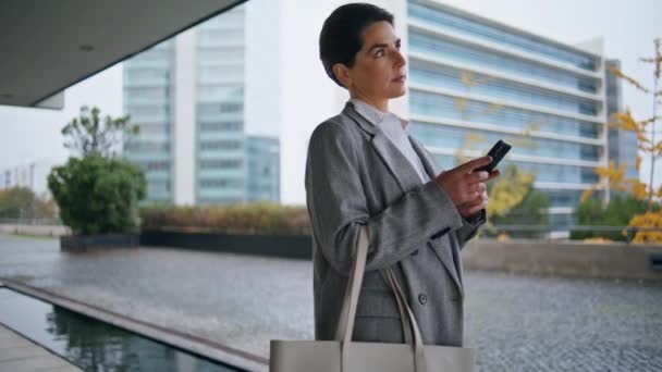 ダウンタウンの女性だけで歩いてスマートフォンを参照してください 思考のマネージャーはオンライン注文を作る電子メールに答える 電話を使ったリラックスした中年のビジネス女性のテキストメッセージ 携帯電話を使ったスタイリッシュなCeo通勤事務所 — ストック動画