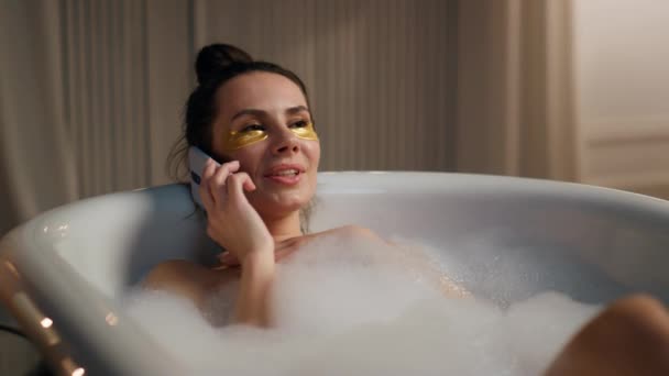 美型冷水浴呼叫电话特写 无忧无虑的女人躺在热水浴缸里享受着愉快的交谈 女士晚上在家里消磨时光 自我护理常规概念 — 图库视频影像