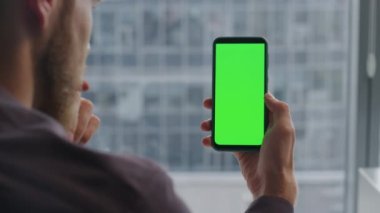 Erkek kollarında yakın çekim cep telefonu var. Tanımlanamayan özenli girişimcinin elinde kroma anahtarı var. Şirket bilgilerini evde analiz ediyor. Çevrimiçi Webinar 'ı yeşil ekranda izleyen isimsiz bir serbest yazar