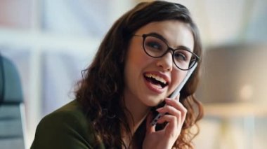 Kapalı mekanda gülümseyen telefonda konuşan mutlu kadın. Modern akıllı telefon oturma odasında konuşan neşeli esmer kızın portresi. Gözlüklü güzel bayan iş için telefon kullanıyor.