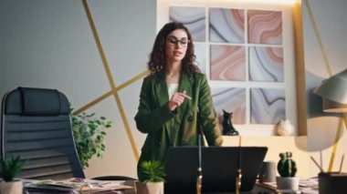 Akıllı kadın yönetici, online sunumda konuşuyor. Ofiste dizüstü bilgisayara bakıyor. Kendine güvenen iş kadını modern işyerinde Webinar 'ı yönetiyor. Esmer kız video konferansında konuşuyor..