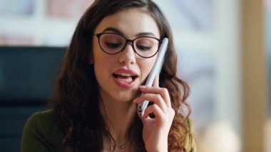 Kendine güveni tam bir bayan patron arıyor. Ofiste oturuyor. Yakın plan. Akıllı telefonlu çekici bir kadının portresi iş talimatları veriyor. Gözlüklü genç iş kadını telefonda konuşuyor.