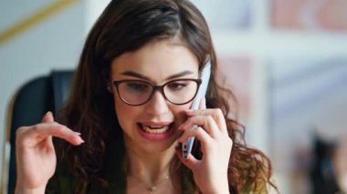 İçeride cep telefonuyla konuşan sinirli iş kadınının portresi. Çekici, ciddi bir iş kadını telefonda tatminsiz konuşmalar yapıyor. Gözlüklü kadın ofis telefonunu arıyor..