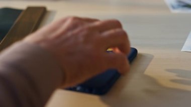 Erkek eli, evdeki ahşap masadan akıllı telefon alıyor. Kapalı alanda yeşil ekran telefon tutan kimliği belirsiz bir adam. Krom tuşuna dokunan erkek parmakları mobil uygulamayı çalıştırıyor.