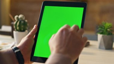 Modern ofiste, Mockup Tablet 'te çalışan kimliği belirsiz bir adam. Yeşil ekran dijital sekmeli masa tutan erkek eller. İşadamı dokunmatik ekran krom anahtar aygıtında kaydırma yapıyor.