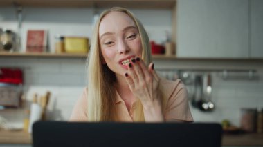 Neşeli çekici kadın, çevrimiçi toplantıyı bitiriyor. Bilgisayarı modern mutfağa kapatıyor. Evdeki video konferanstan sonra web kamerasına el sallayan mutlu sarışın kızın portresi.
