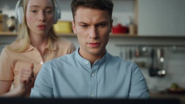 Evde uzaktan çalışan meşgul bir işadamının portresi. Neşeli bir eş arka planda kablosuz kulaklıklarla dans ederken. Mutfakta oturup finansal raporlar hazırlayan çekici bir finansçı..