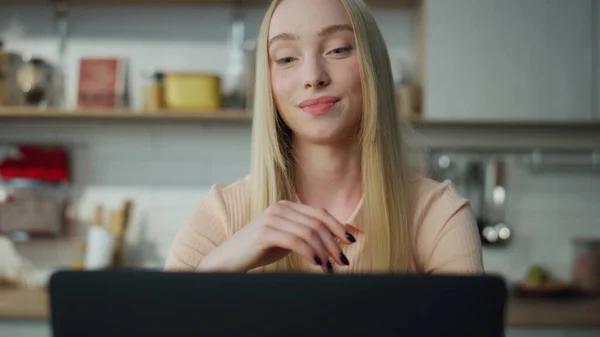 兴高采烈的女经理坐在自家厨房的近旁 挥手完成了在线会议 金发迷人的女孩说再见视频通话 漂亮的女士正在用笔记本电脑远程工作 — 图库照片