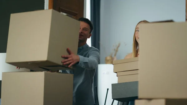 Young family carrying cardboard boxes with furniture stuff to new apartment. Happy spouses furnish purchased flat after relocation. Smiling couple excited by moving in comfortable rent house.