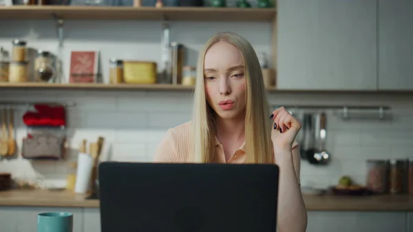 有思想的女会计在家里厨房的笔记本电脑上远程工作 困惑的金发姑娘看着公司的财务单据 认真的专业经理人在荧幕上看书 — 图库照片