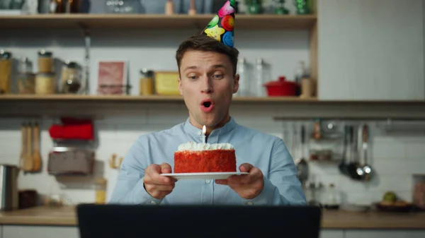 オンライン会議の友人との挨拶だけでキッチンに座っておいしいケーキで誕生日を祝う幸せな魅力的な男を閉じます 陽気な男で明るいです帽子作りバーチャルパーティー使用してビデオ通話 — ストック写真