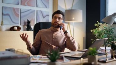 Orta yaşlı, kendine güvenen bir iş adamı modern iş yerinde akıllı telefondan konuşuyor. Sakallı yönetici telefon kullanarak iş veriyor. Odaklanmış girişimci telefon kulübesini arıyor..