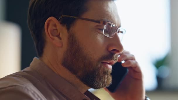 閉鎖ひげそりのビジネスマンは屋内の携帯電話で通話を終了します オフィスで働く現代的なスマートフォンを持つ中年男性に焦点を当てました 職場で電話で話す魅力的な深刻なマネージャーの労働者 — ストック動画