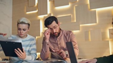 Kurul masasında oturan yorgun ofis çalışanları iş meselelerini birlikte çözmeye çalışıyorlar. Genç adam mola vermek için meslektaşlarına kahve fincanı getiriyor. Müteşekkir iş arkadaşları çalışma sahasında sıcak içecek alıyorlar.