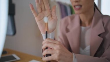 Blogcu el, fırçanın yakın çekimde abonelerle konuştuğunu gösteriyor. Güzellik blogu kaydeden kadın, yüz hatları çizen hayat hacklemelerini açıklıyor. Makyaj sanatçısı seyircilere temel teşkil ediyor