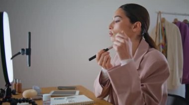 Güzellik blogu yazarken yüzünü fırçalayan kız etkiler. Yakın çekim makyaj sanatçısı internet izleyicilerine pudra uyguluyor. Akıllı telefon kamerasına konuşan bir kadın evde yüz estetiği öneriyor.