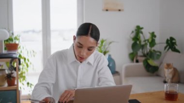 Modern ofiste Webinar dinleyen çalışkan bir öğrenci yakın çekimde notlar yazıyor. Kulaklık pozitif kadın evde bilgisayar dersleri öğreniyor. Zeki bayan internette çalışıyor. Uzaktan eğitim kavramı
