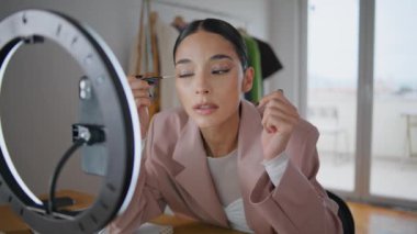 Blogcu kız eve yakın çekim yaparken göz kalemi kullanıyor. Moda kadını makyaj video blogu kaydediyor. Güzellik etkileyicisi sosyal medya takipçileriyle rutin yüz tanıma programını paylaşıyor 