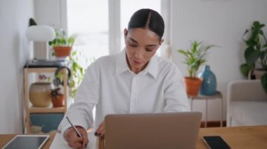 Öğrenci kız internette notlar yazıyor. Yakın çekimde öğreniyor. Kulaklıklı kadın laptop dersleri izliyor. Gayri resmi ofiste Webinar dinliyor. Zeki bayan uzaktan çalışıyor. Yurtiçi eğitim kavramı