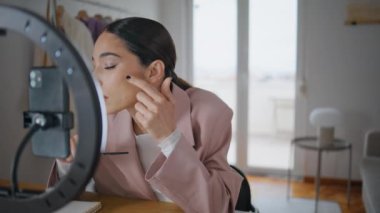Makyaj eleştirisi yapan nüfuzlu kişi, odasındaki akıllı telefon kamerasına yakın çekim yapıyor. Vizeci kadın evdeki internet işitme sistemiyle konuşurken video blogu kaydediyor. İnternet 'te güzellik ürünleri öğrenen bir bayan