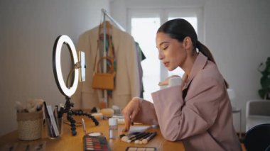 Bayan blogcu evde kozmetik ürünleri tavsiye ediyor. Popüler nüfuzlu vlog kaydedicisi fırçaların cep telefonu kamerasıyla konuştuğunu gösteriyor. Makyaj videosunu akıllı telefona yayınlayan kadın yüz sanatçısı 