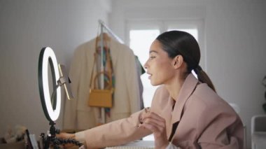 Güzellik blogcusu stüdyo kapanışında düğmeye basıyor. Makyöz, cep telefonu ekranı görünümlü, lamba teçhizatı ayarlarını seçiyor. Mutlu kadın tripodda cep telefonu kullanıyor.