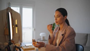 Kadın blogcu evdeki cep telefonu kamerasına sima uyguluyor. Popüler nüfuzlu kişi cep telefonuyla konuşurken yüzünü pudralıyor. Makyaj videosu yayınlayan kadın yüz ressamı.