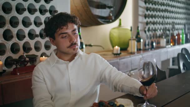 Jovem Pensativo Segurando Taça Com Vinho Tinto Sentado Acolhedor Restaurante — Vídeo de Stock