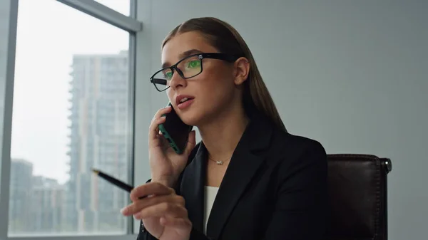 Woman executive talking smartphone in office closeup. Focused manager consulting client discussing marketing project with business partner. Beautiful businesswoman freelancer making call at workplace