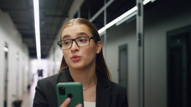 Gülümseyen iş kadını video görüşmesini yakından konuşuyor. Serbest çalışanın ofis merkezine gidip online konferans düzenlediği için mutlu. Güzel bir kız iletişim kurarken akıllı telefon kullanır. Şirket yaşam tarzı kavramı