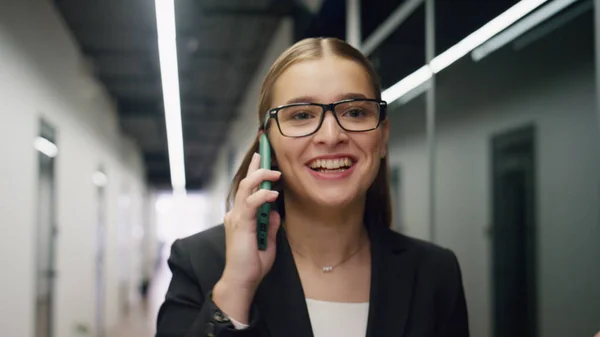 stock image Cheerful woman talking mobile phone closeup. Beautiful manager speaking partner sharing successful news in contemporary office. Happy businesswoman assistant enjoying conversation walking hallway.