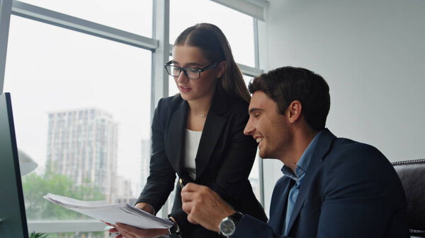 Офисная команда работает за компьютером. Улыбающиеся маркетологи обсуждают документы, анализирующие данные на рабочем месте. Красивая женщина-босс объясняет, как помочь сотруднику. Концепция набора рабочих мест.